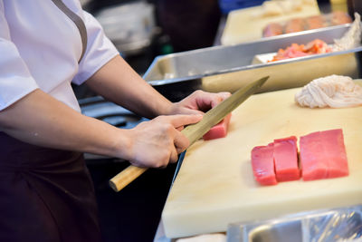 Midsection of chef cutting meat in commercial kitchen