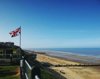 Low section of person on beach against blue sky