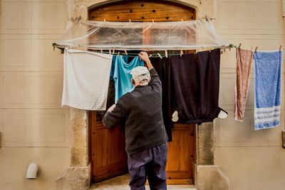 Rear view of man hanging laundry on clothesline