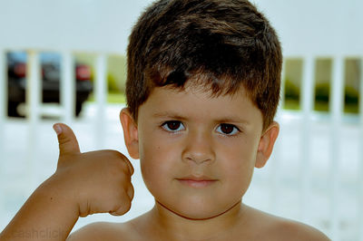 Close-up portrait of shirtless boy showing thumbs up sign