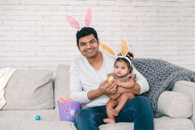 Father and daughter sitting together on sofa at home