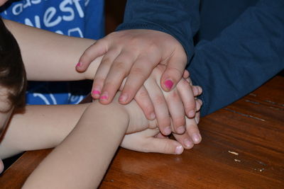 Cropped hands of friends stacking hands on wooden table