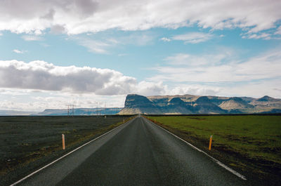 Road amidst field against sky