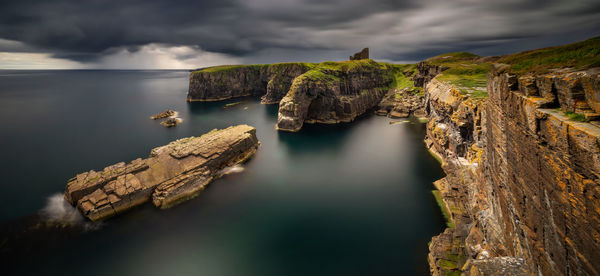 Panoramic view of rock formation in sea against sky