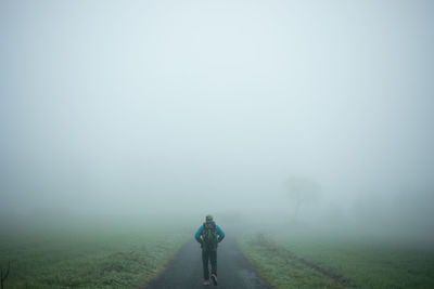 Rear view of man walking on road