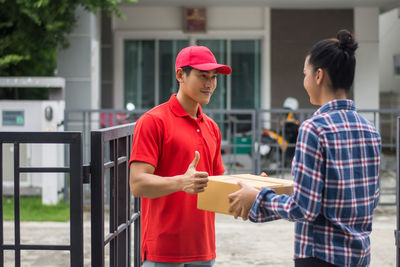 Man delivering package to female customer at gate