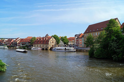 Buildings by river against sky in city