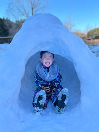 Portrait of smiling boy standing on snow covered landscape