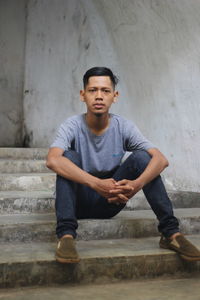 Portrait of boy sitting on staircase against wall