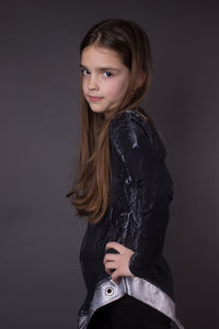 Portrait of teenage girl standing against black background