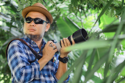 Man holding camera against trees