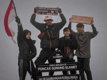 Portrait of happy friends standing against gray background