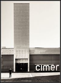 People walking on modern building against clear sky