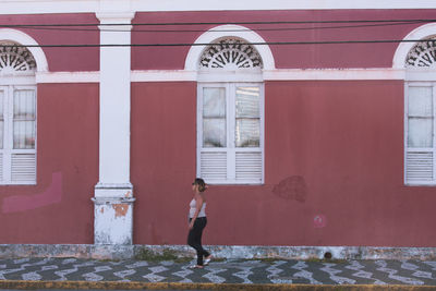 Side view of woman standing against building