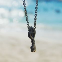 Close-up of key hanging chain against sky