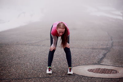 Full length of tired young woman walking on road foggy weather