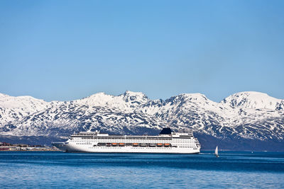 Scenic view of sea by snowcapped mountains against sky