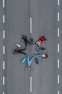 Female friends with arms outstretched lying down on road