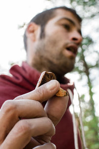 Low angle view of man holding mushroom while standing outdoors