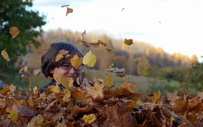 Portrait of young woman with autumn leaves on field