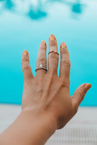 Female hand with ring jewelry on swimming pool blured background. vacation travel summer concept. 