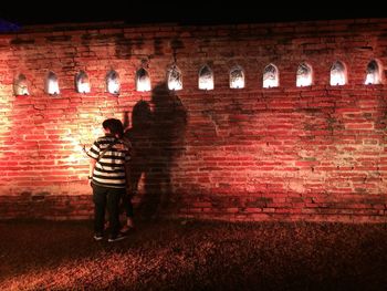 Rear view of man standing against brick wall