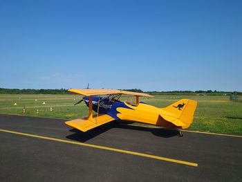 Airplane on field against clear blue sky