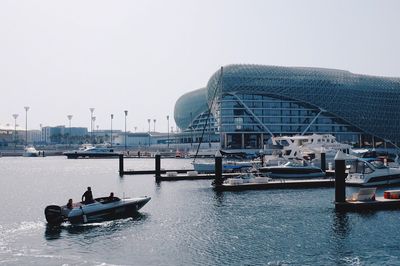 Boats moored at harbor against clear sky