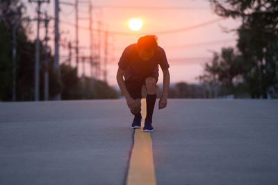 Man running on street against sky during sunset