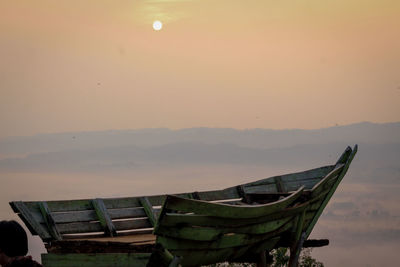 Boat moored on beach against sky during sunset