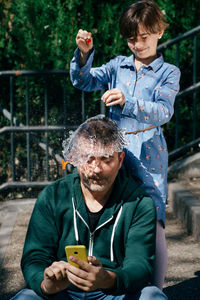 Girl splashing water over father head outdoors