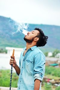 Young man smoking hookah against mountain