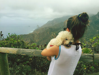 View of a dog looking at mountain against sky