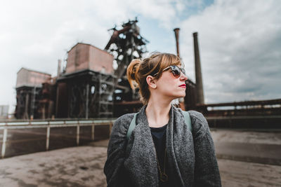 Beautiful woman looking away while standing against sky