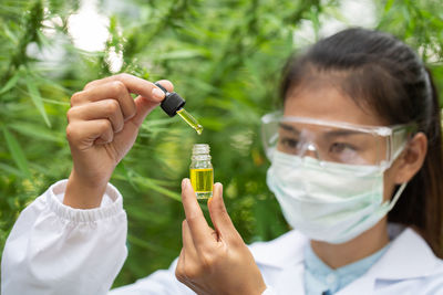 Portrait of woman holding cannabidiol in dropper