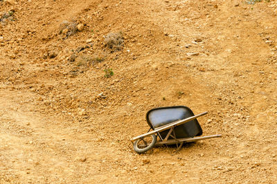 High angle view of abandoned fallen wheelbarrow on dirt