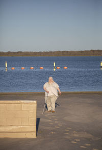 Rear view of man on beach against clear sky