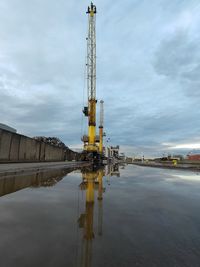 Cranes in factory against sky