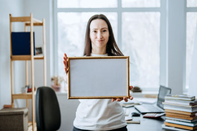 Frame picture, poster, diploma, certificate mockup in female hands. young brunette woman holding