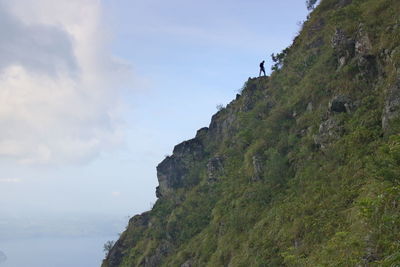Low angle view of cliff by sea against sky