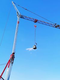 Low angle view of crane against clear blue sky