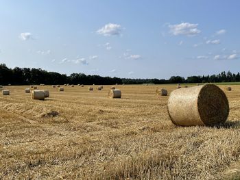 Hay bales on field against sky