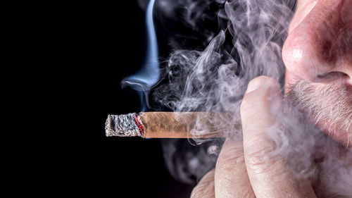 Man smoking cigar against black background