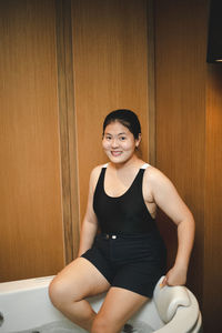 Portrait of young woman standing against yellow wall