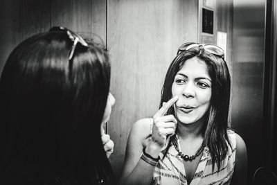 Young woman with reflection on mirror in elevator