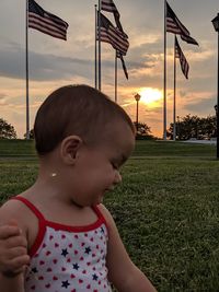 Boy playing on field against sky during sunset