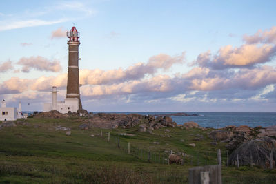 Lighthouse by sea against sky