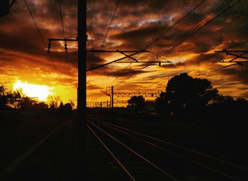 Silhouette railroad tracks against sky during sunset