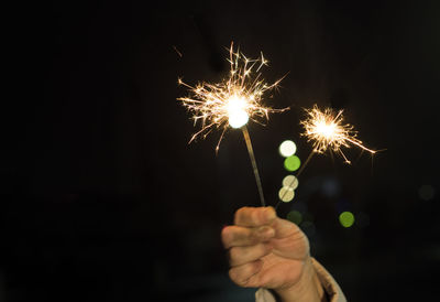Cropped hand of child holding lit sparklers