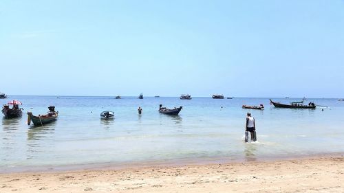 Group of people on beach against clear sky